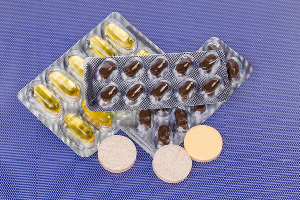 шипучие таблетки, различные капсулы в блистерной упаковке на голубой поверхности - Фото, изображение