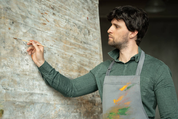 Painter man working in a modern abstract oil canvas in his studio - Φωτογραφία, εικόνα