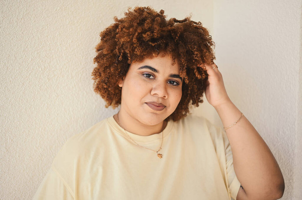 Beautiful happy smiling curvy plus size African black woman afro hair with make up posing in beige t-shirt on white background. Body imperfection, body acceptance, body positive and diversity concept - Photo, Image
