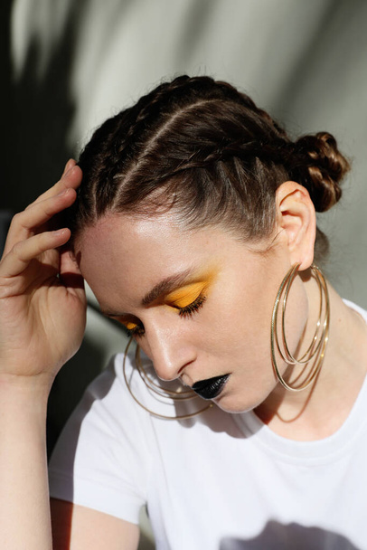 Vertical headshot of young caucasian woman with braids and make-up. Outdoor. - 写真・画像