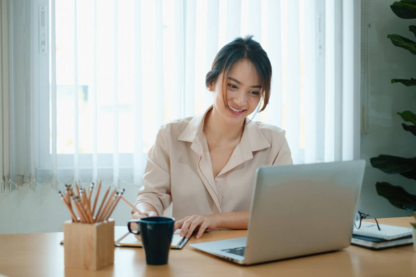 Eine fröhliche Frau konzentriert sich auf ein Webinar auf ihrem Laptop. - Foto, Bild