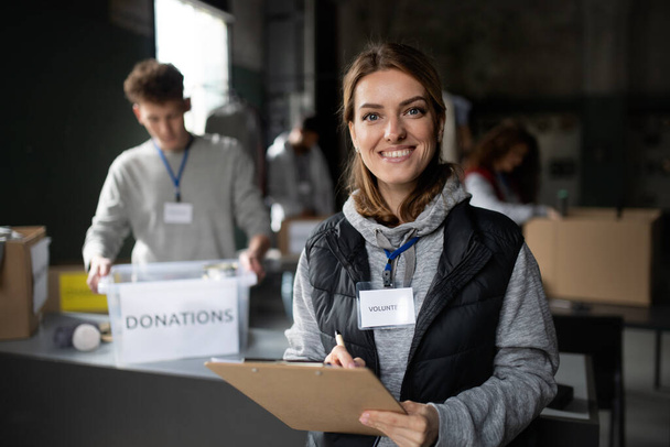 Woman volunteer working in community charity donation center, looking at camera. - Photo, Image