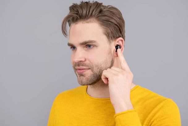 bluetooth headset device accessory. new bluetooth technology. Man point finger at wireless earbud earphones inside ear. Listening with headphones. make music a pleasant experience. - Foto, afbeelding