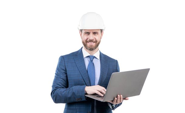 hombre de negocios feliz en traje y casco de seguridad wotking en la computadora en línea aislado en blanco, negocio ágil. - Foto, imagen