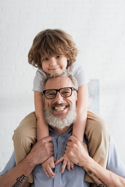 Cheerful boy and grandfather smiling at camera  - Foto, imagen