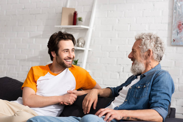 Cheerful man looking at mature father  - Photo, Image