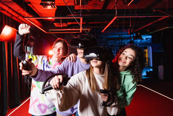 Ευτυχισμένοι διαφυλετικοί έφηβοι δείχνουν ναι χειρονομία κοντά ενθουσιασμένοι φίλοι σε ακουστικά VR - Φωτογραφία, εικόνα
