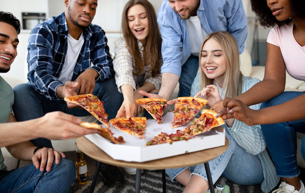 Mutlu çok ırklı arkadaşlar sohbet ediyorlar, birlikte pizza yiyorlar, evde küçük bir parti veriyorlar. - Fotoğraf, Görsel