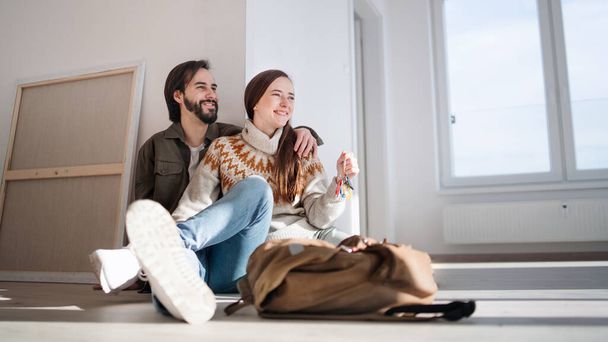 Young couple with keys moving in new flat, new home and relocation concept. - 写真・画像