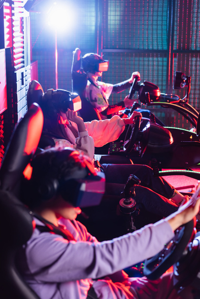 teenagers in vr headsets playing racing game in car simulators - Photo, Image
