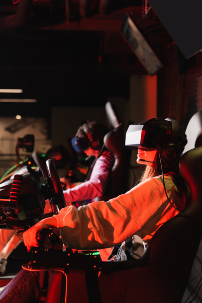 teenage friends in vr headsets gaming on car racing simulators  - Фото, зображення