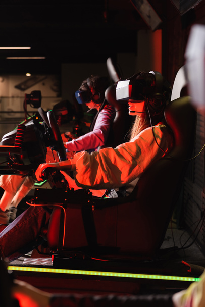 teenage friends gaming on car racing simulators on blurred foreground - Fotografie, Obrázek