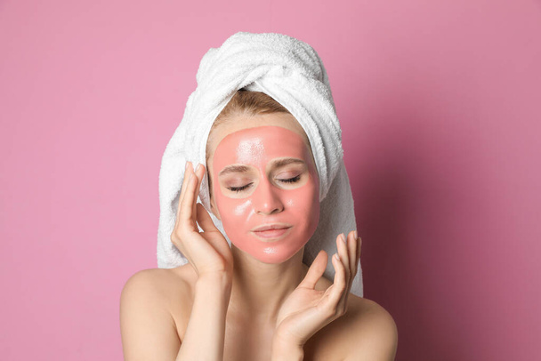 Young woman with pomegranate face mask on pink background - Foto, Imagen