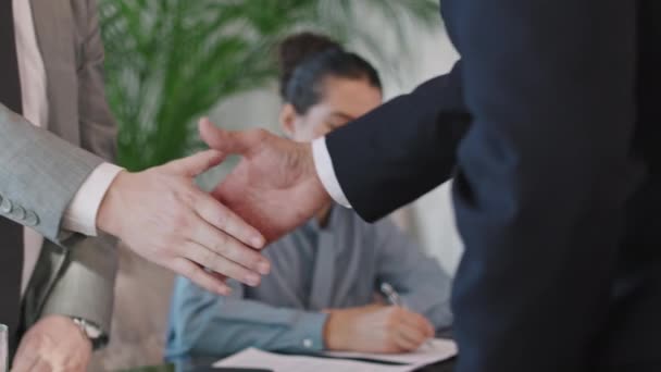 Медленный крупный план неузнаваемых деловых партнеров-мужчин, пожимающих руку после успешной сделки во время официальной встречи в ярком современном конференц-зале - Кадры, видео