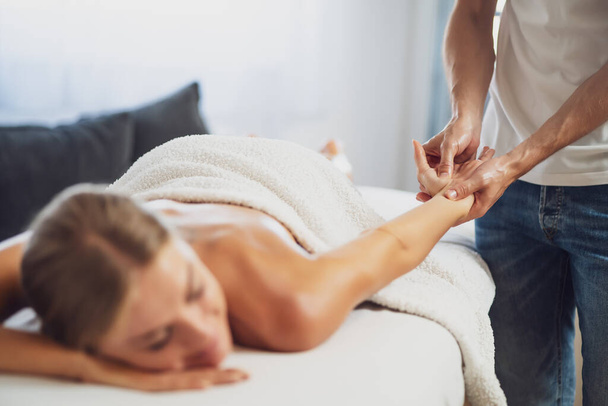 Profesyonel masör terapi masajı yapıyor. Kadın evinde masaj yaptırıyor. Genç kadın vücut masajı yaptırıyor.. - Fotoğraf, Görsel