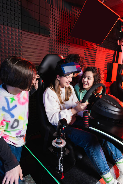 vidám interracial tizenévesek nevetnek közelében ámult lány autós szimulátor - Fotó, kép