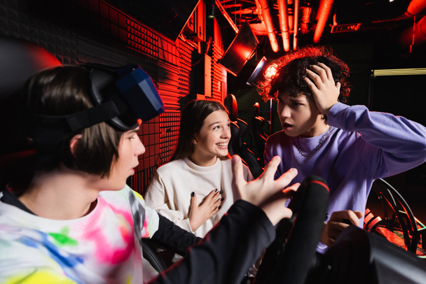 érzelmi játékosok beszél és gesztikulál közelében autóverseny szimulátor - Fotó, kép