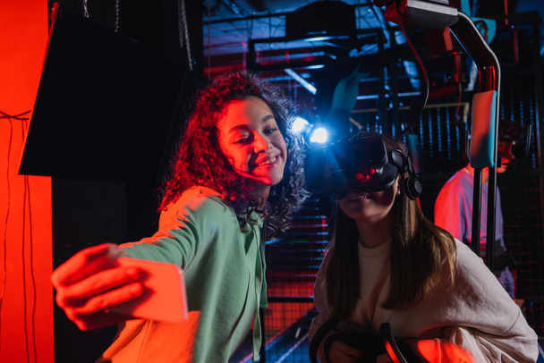 cheerful african american girl taking selfie with friend in vr headset - Photo, Image