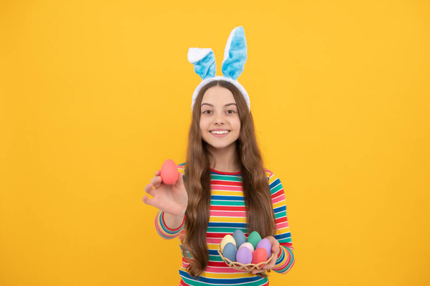 щаслива великодня дівчина-підліток у вухах кролика, що тримає розфарбовані яйця для святкового полювання на яйце, великодні канікули
. - Фото, зображення