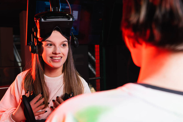 excited girl looking at blurred friend in vr game zone - Foto, immagini