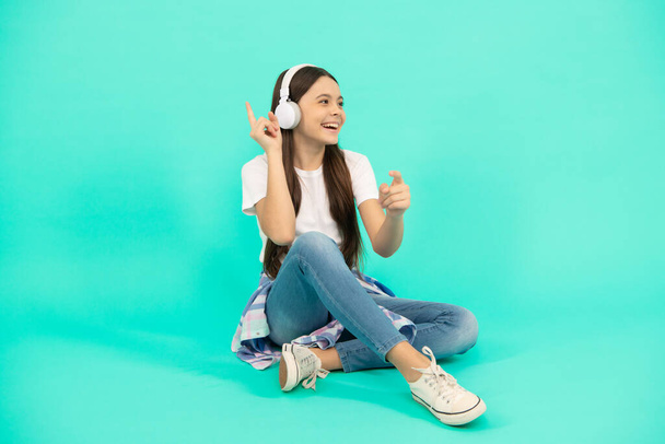 Énekeljünk. gyermek modern fülhallgatóban. online oktatás. Vissza az iskolába. boldog tini lány fülhallgatóban. Hallgasson zenét. vezeték nélküli fejhallgató tartozék. új technológia. gyermekkori fejlődés. - Fotó, kép