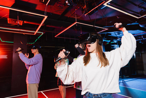 excited girl in vr headset gaming near friends in play room - 写真・画像