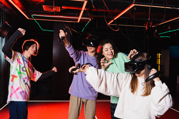 african american girl showing scaring gesture near friends in vr headsets - Photo, Image