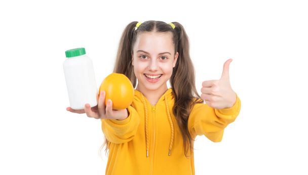 happy kid offer orange fruit and vitamin pill in jar bottle isolated on white, refreshing - Photo, image