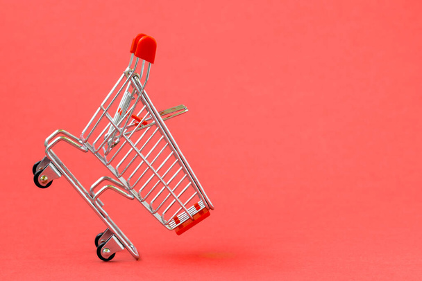 Empty shopping cart on a red background. Grocery hand cart. - Photo, Image