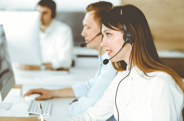 Group of diverse operators at work in call center. Beautiful asian woman sitting in headset at customer service office. Business concept - 写真・画像