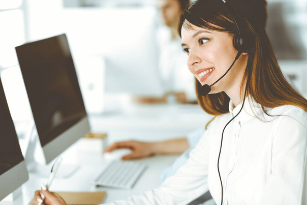 Group of diverse operators at work in call center. Beautiful asian woman sitting in headset at customer service office. Business concept - Foto, Imagem