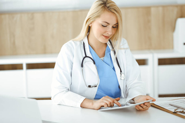 Woman-doctor standing in hospital or clinic and using tablet pc. Data and best service in medicine and healthcare - Foto, imagen