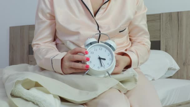 Γυναίκα στο κρεβάτι κρατώντας το ξυπνητήρι clock.Controlling έννοια του προσωπικού χρόνου - Πλάνα, βίντεο