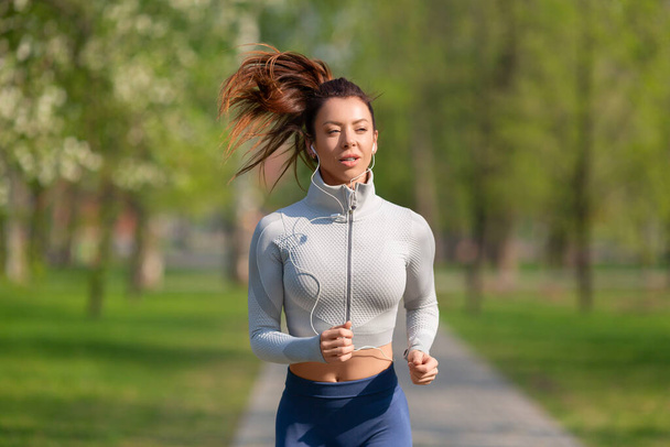 Женщина, бегающая в парке рано утром. Привлекательная женщина сохраняет форму и здоровье. - Фото, изображение