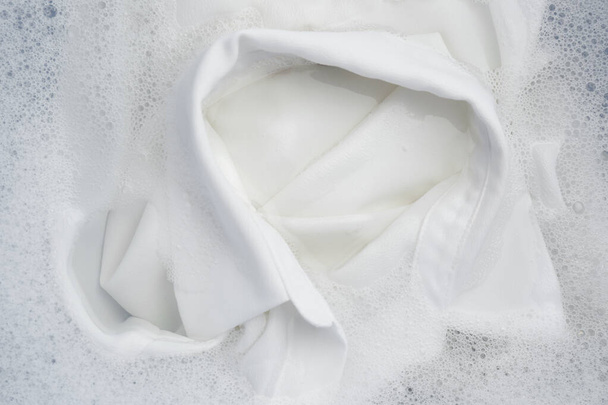 White clothing in suds, top view. Hand washing laundry - Фото, изображение