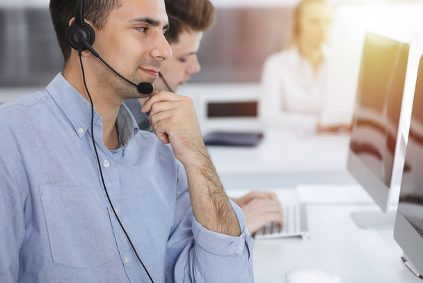 Call center. Group of casual dressed operators at work. Adult businessman in headset at customer service office. Telesales in business - Foto, Bild