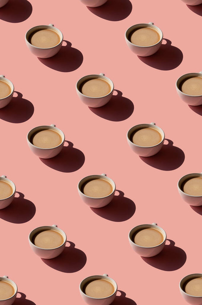 ピンクの背景にコーヒーパターンのカップ。日光の最小限のトレンディーなコンセプト - 写真・画像