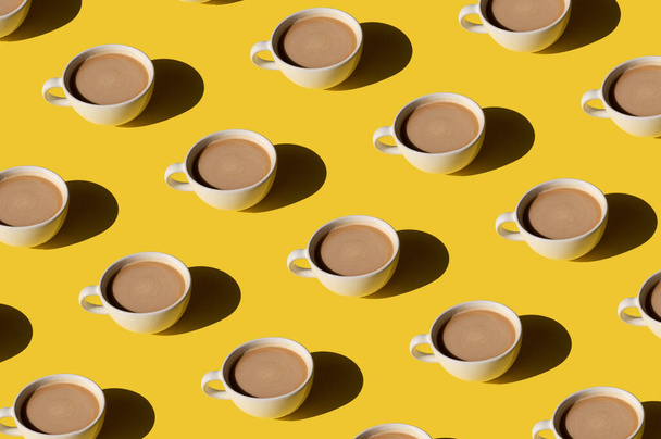 Weiße Tasse Kaffee mit Milchmuster auf gelbem Hintergrund. Sonnenlicht minimales trendiges Konzept - Foto, Bild