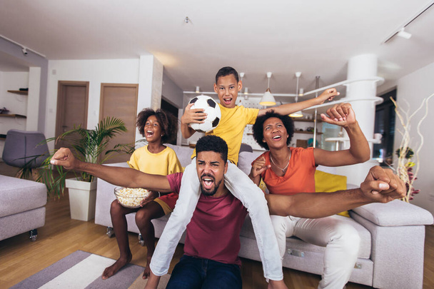 Happy african american family watching soccer match on television in living room at home. - Photo, Image