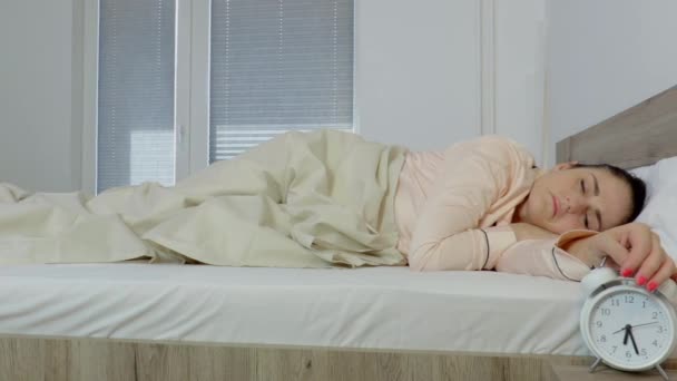 Mujer siendo despertada por su despertador en su dormitorio - Metraje, vídeo