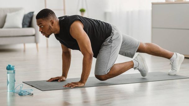 Sporty African Man Doing Running Plank Exercise At Home, Side-View - Photo, image