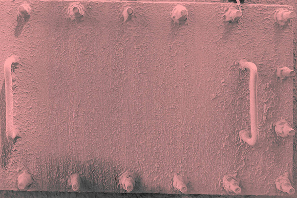 μια ροζ μεταλλική καταπακτή με δύο ορθογώνιες λαβές είναι βιδωμένη γύρω από την περίμετρο - Φωτογραφία, εικόνα