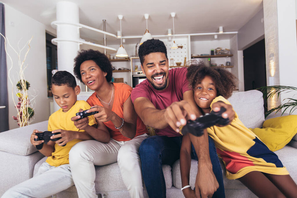 Familia afroamericana jugando videojuegos juntos y divirtiéndose en casa - Foto, imagen