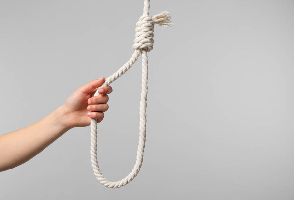 Woman holding rope noose on light grey background, closeup. Space for text - Foto, Bild