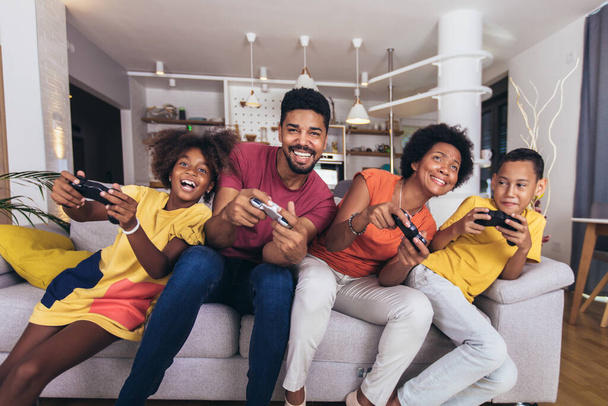 Afro-Amerikaanse familie spelen videospelletjes samen en plezier hebben thuis - Foto, afbeelding