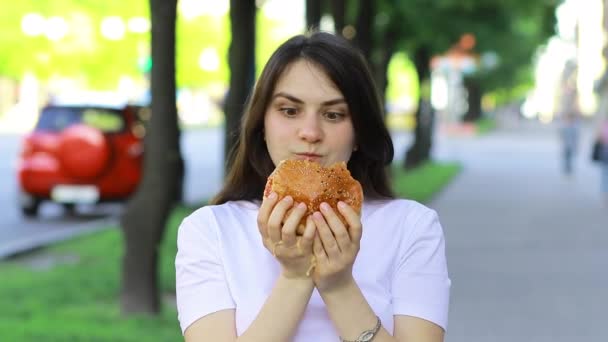 Mujer morena come en exceso en una hamburguesa en la calle. Gluttonía, exceso de calorías y bulimia. - Imágenes, Vídeo
