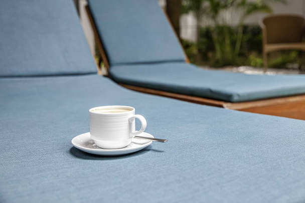 La tasse à café placée sur le lit sanbed a une housse de siège bleue - Photo, image