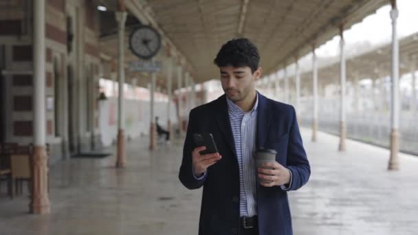 Businessman with smartphone and coffee walking on street - Кадри, відео