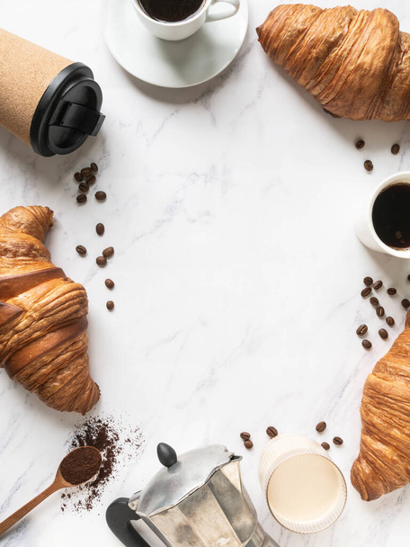 Vlakke lay frame van kopjes koffie en croissants op marmeren achtergrond. Frans ontbijt concept. Bovenaanzicht. Kopieerruimte - Foto, afbeelding