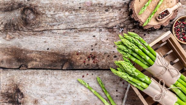 Asparagus. raw stems of asparagus on a wooden background. Long banner format, top view. - Foto, Imagen